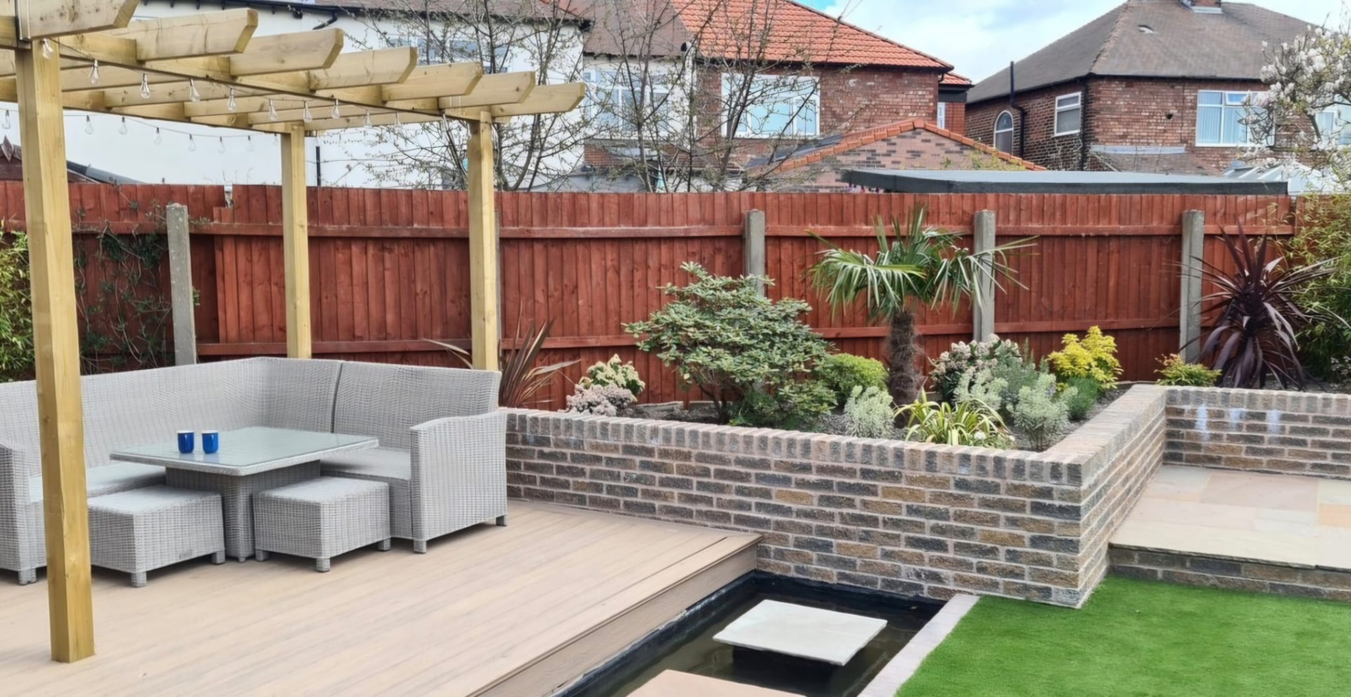 Landscaped garden with timber pergola, seating, raised brick planting and water feature